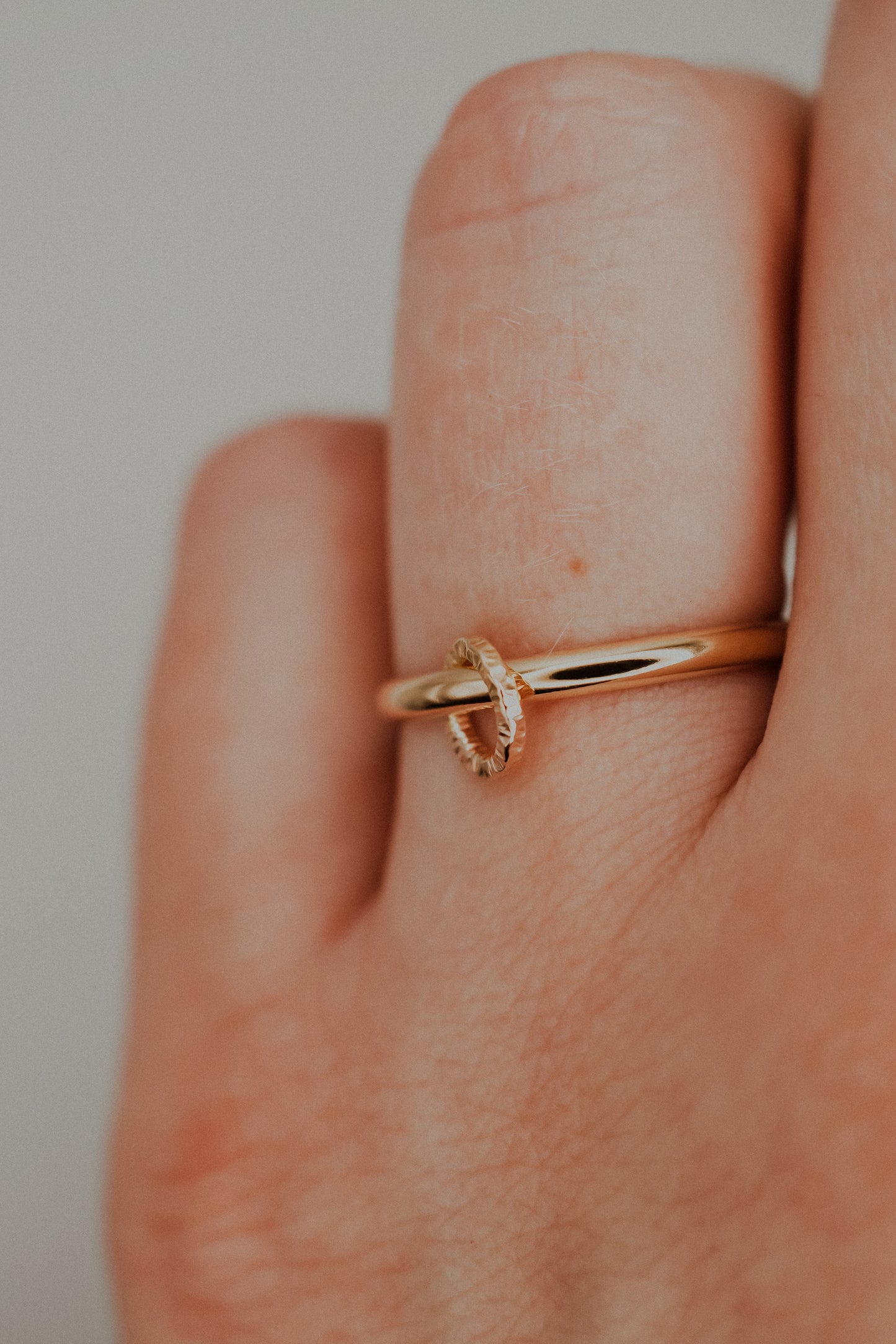 Gold ring on a finger against a neutral background