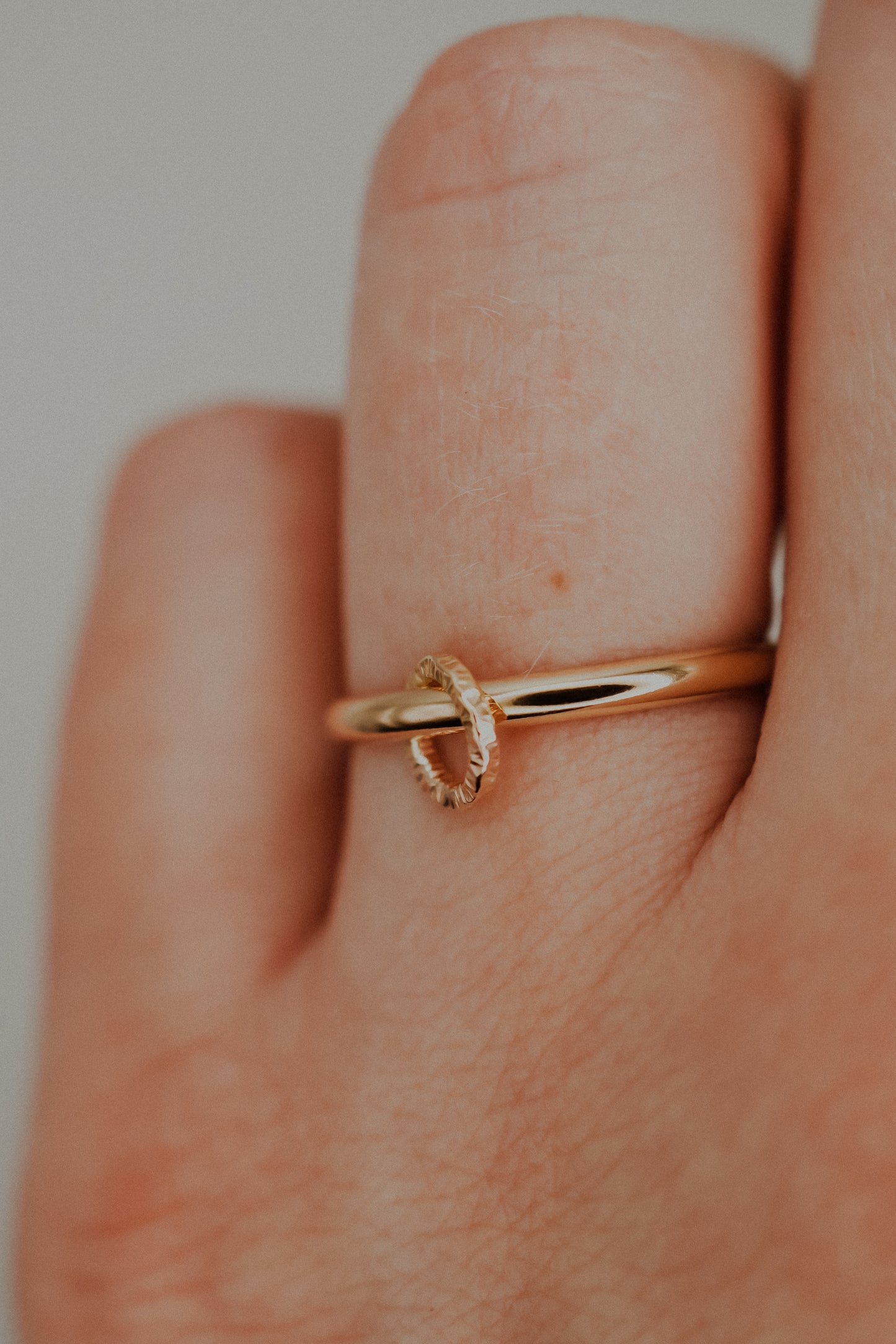 Gold ring on a finger with a plain background