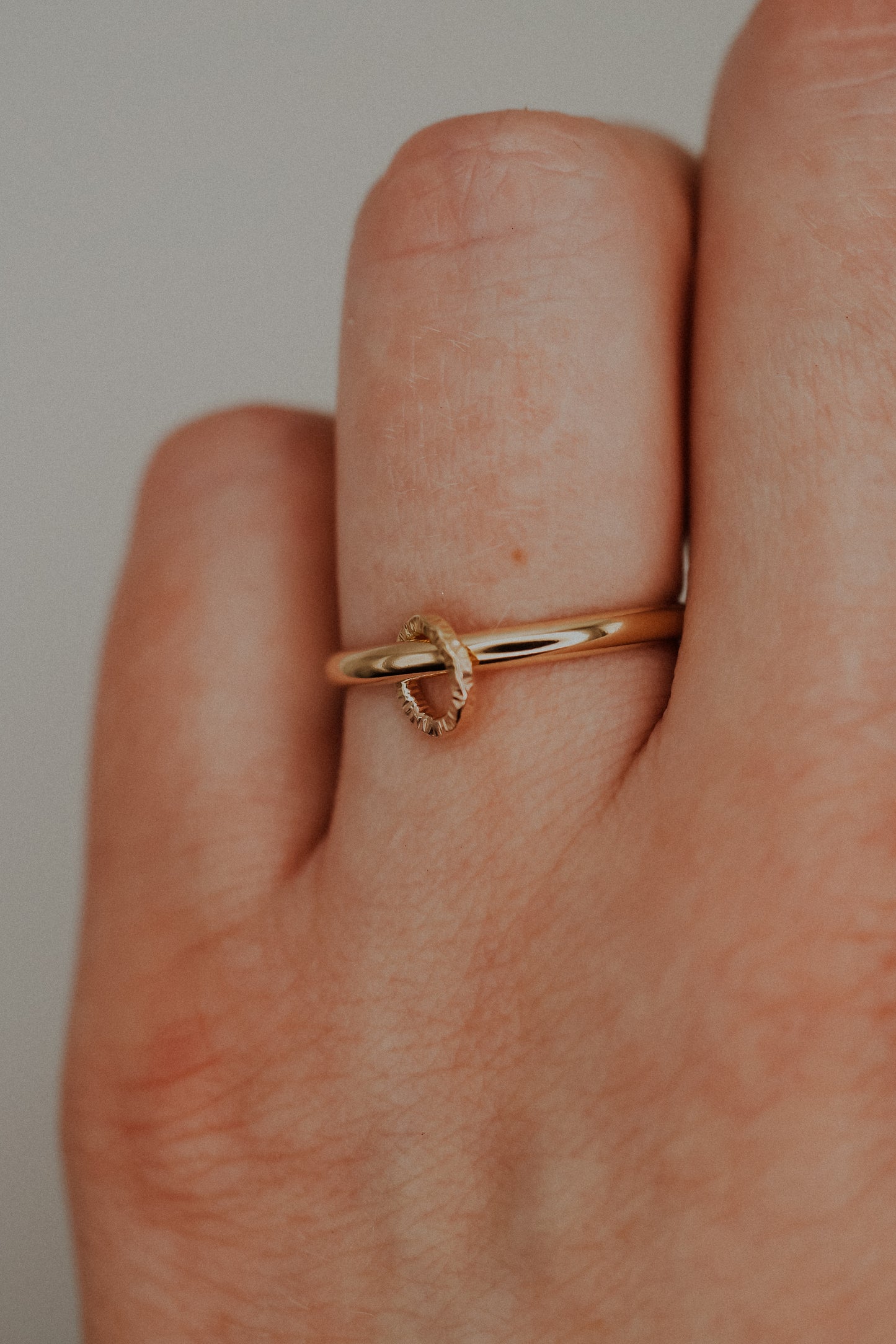 Gold ring on a finger against a neutral background