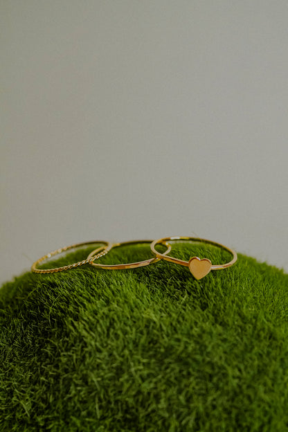 Gold heart-shaped ring on a green textured surface with a neutral background