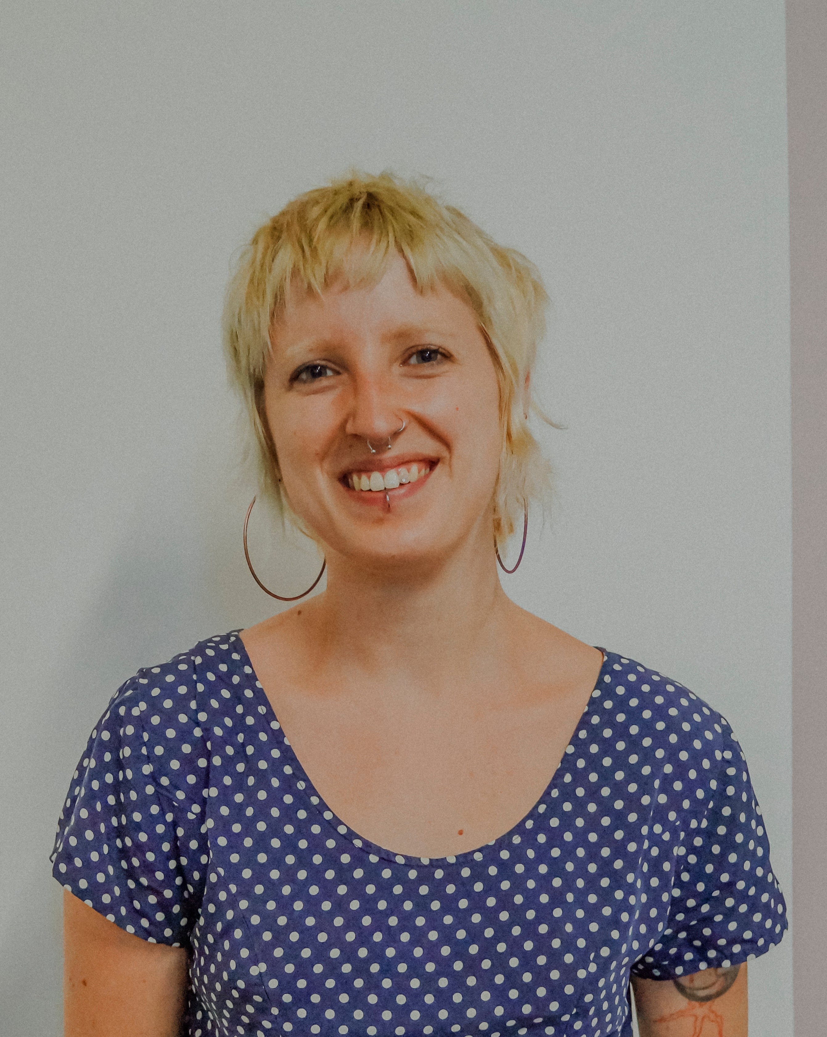 Woman wearing a blue polka dot shirt against a plain background