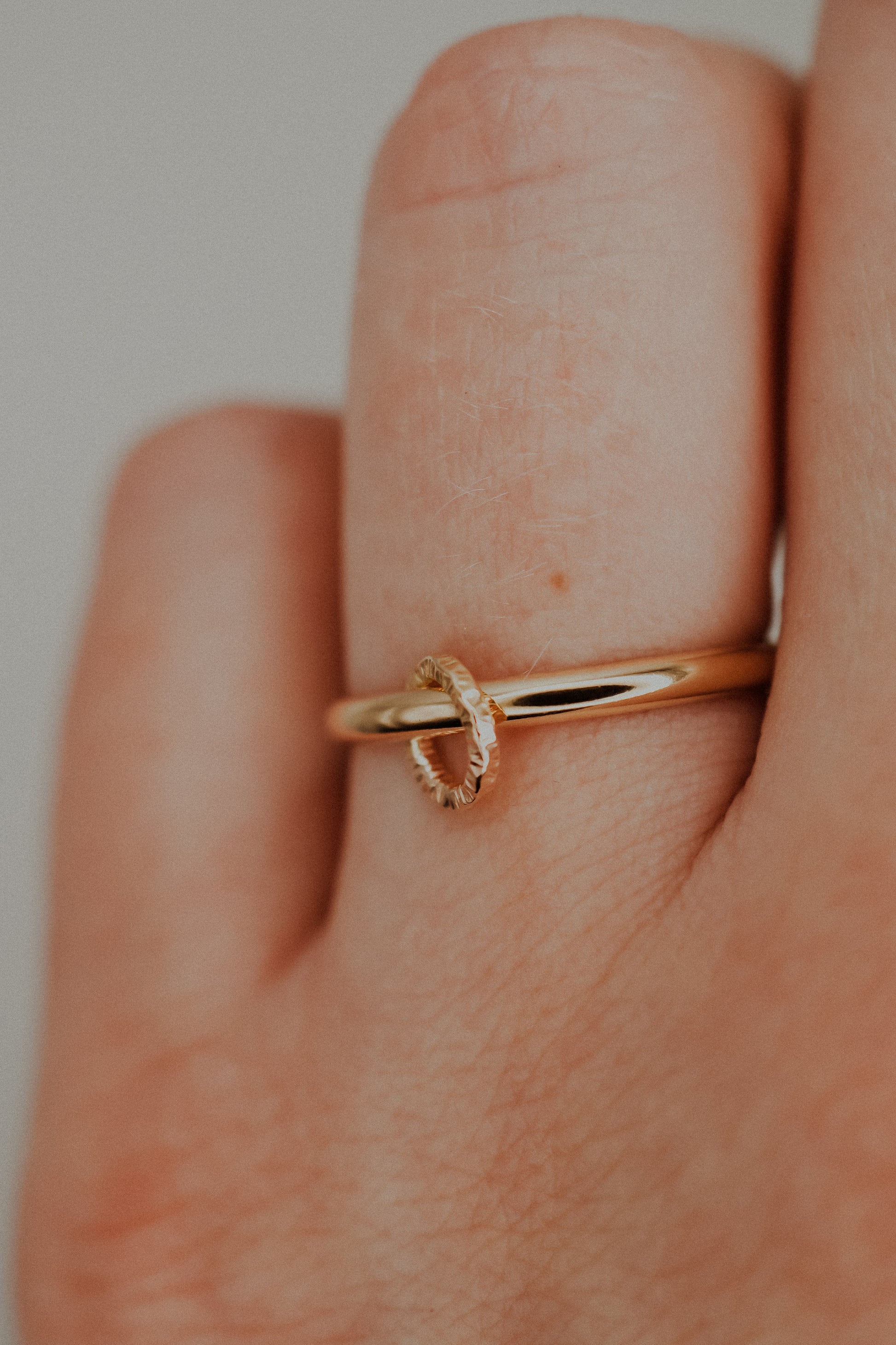 Gold ring on a finger with a plain background
