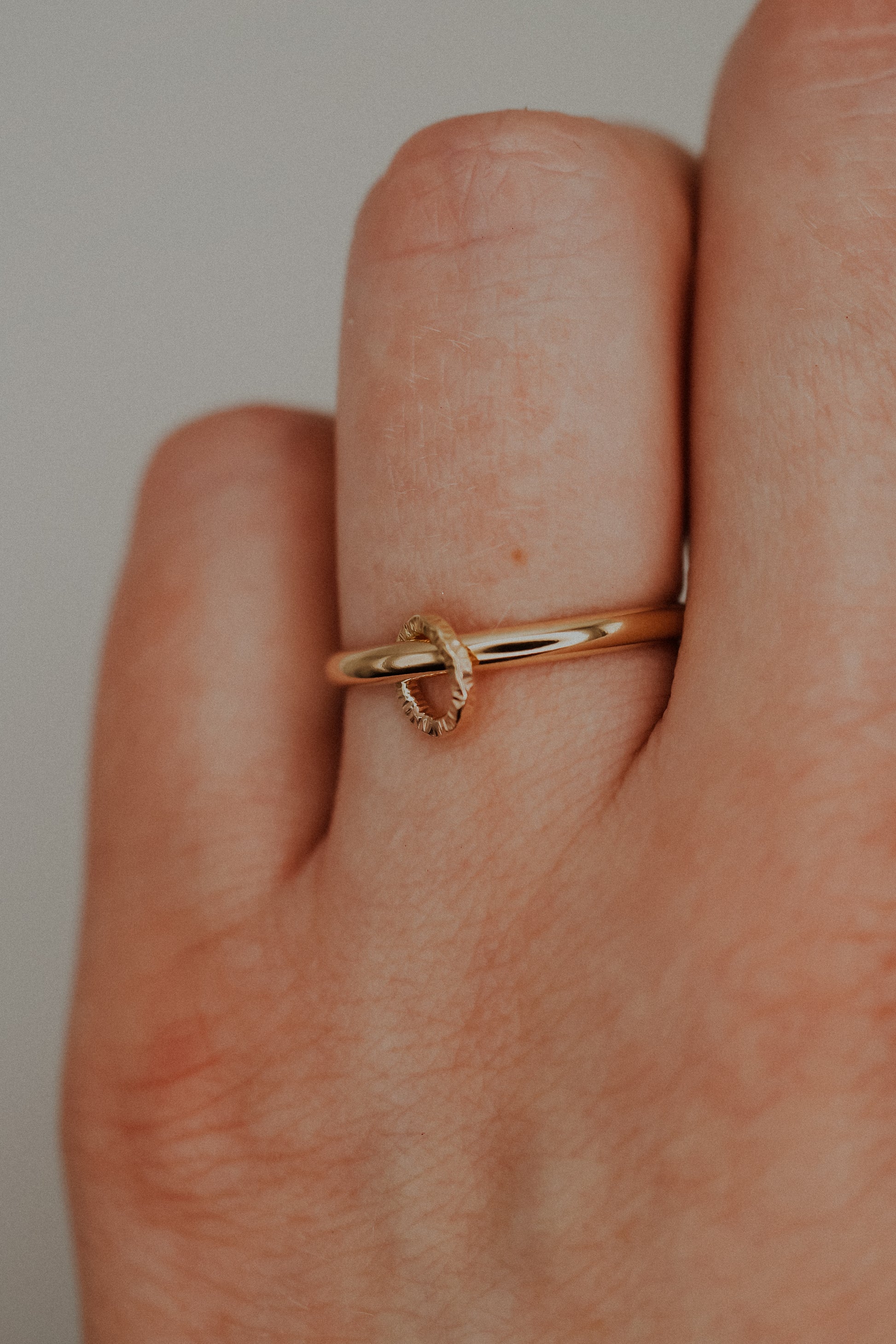 Gold ring on a finger against a neutral background