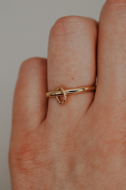 Gold ring on a finger against a neutral background