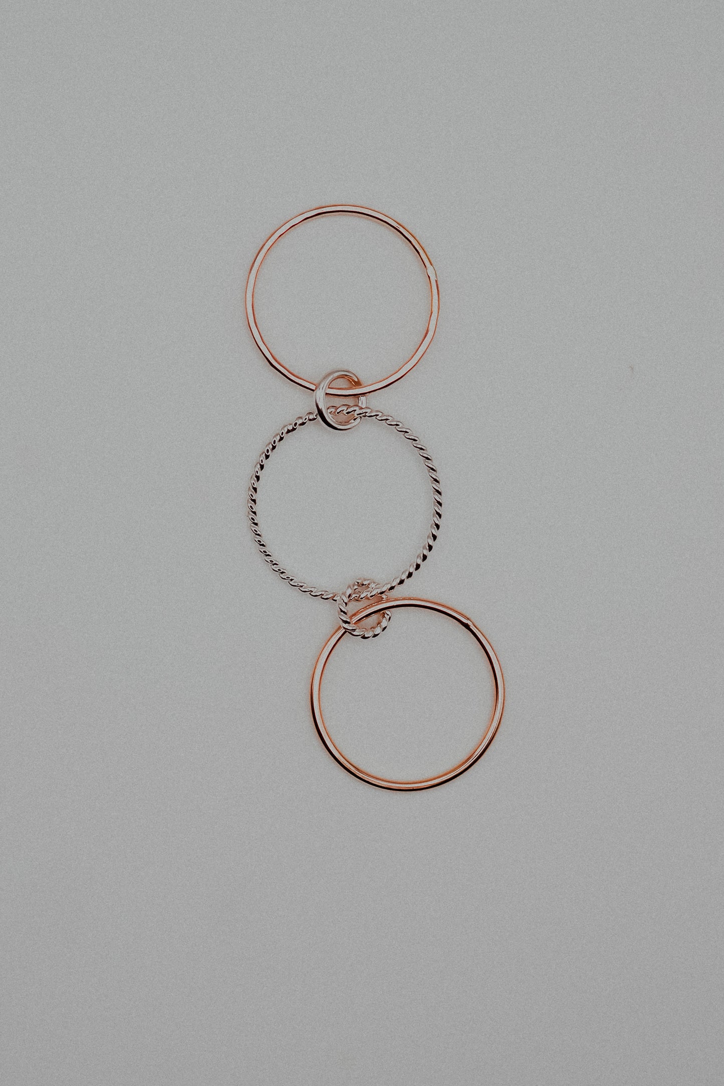 Rose gold and silver interlocking rings on a gray background
