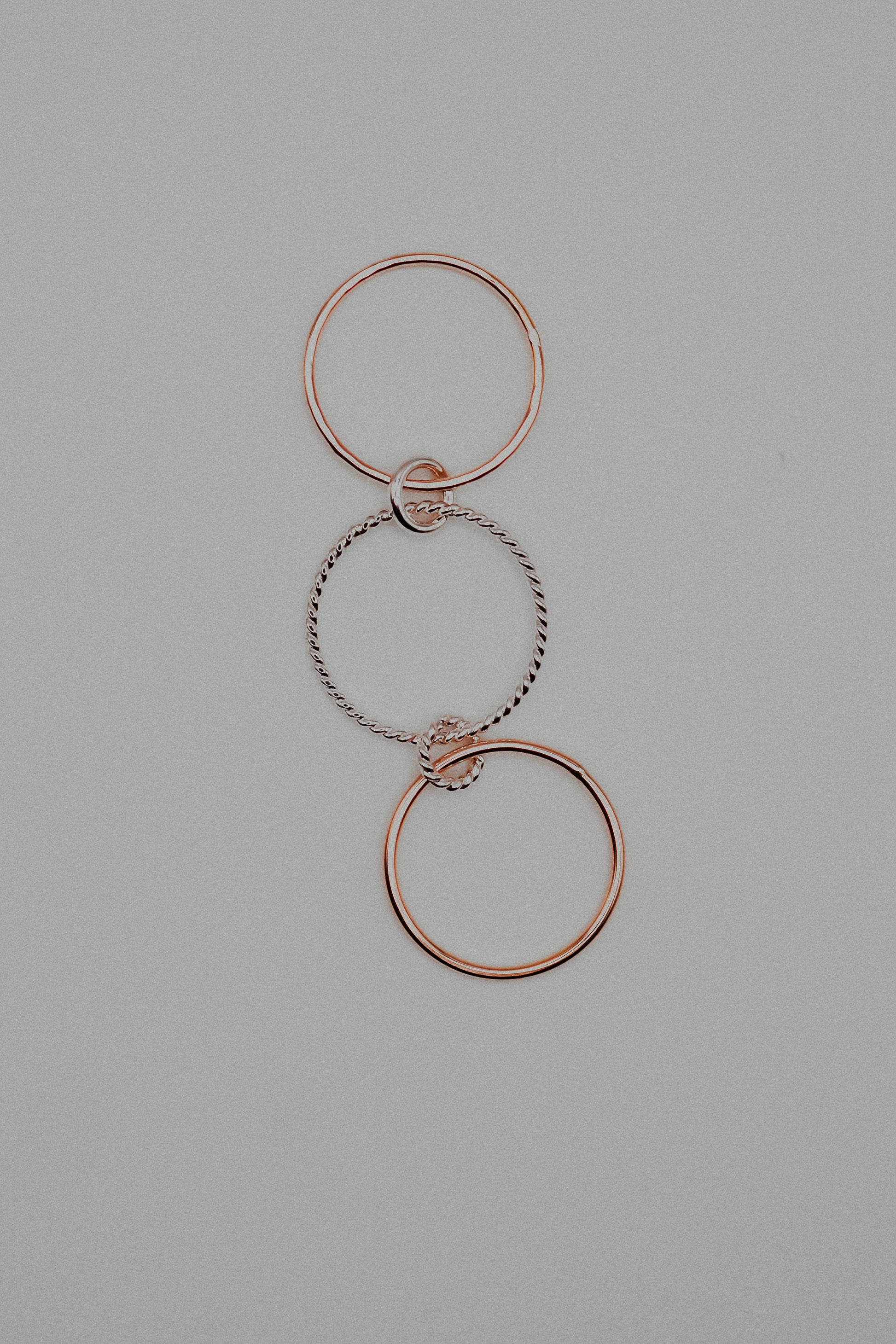Rose gold and silver interlocking rings on a gray background