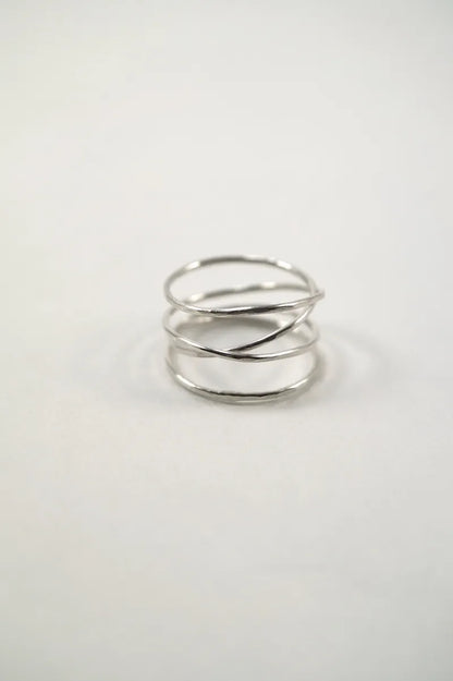 A wraparound ring with four wraps in a thin, Sterling Silver metal with a lightly hammered/faceted finish on a white background.